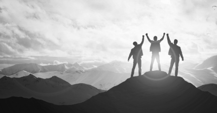 Three professionals standing on top of a mountain